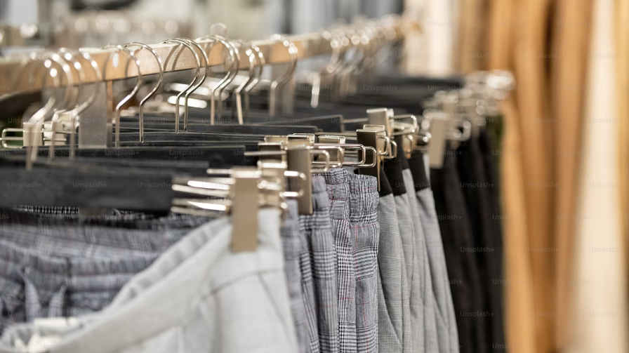 Collection of men's trousers on a clothing rack.