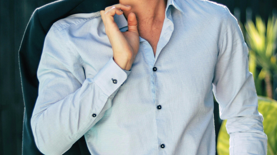 Stylish man in a light blue shirt with a blazer slung over his shoulder